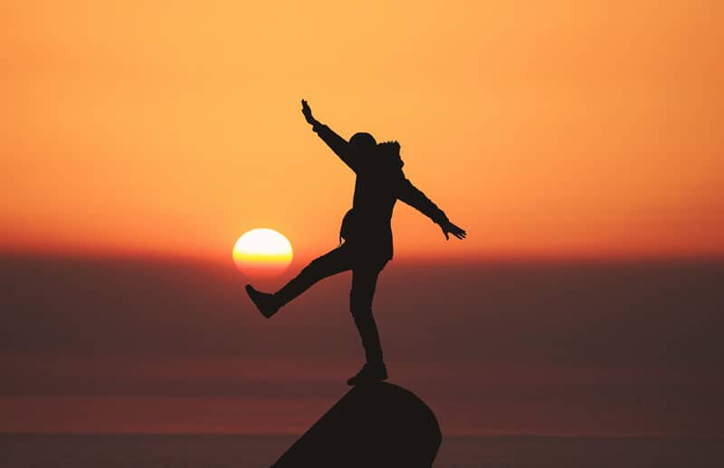 Person balancing against a sunset backdrop - Holistic Wellness Explained